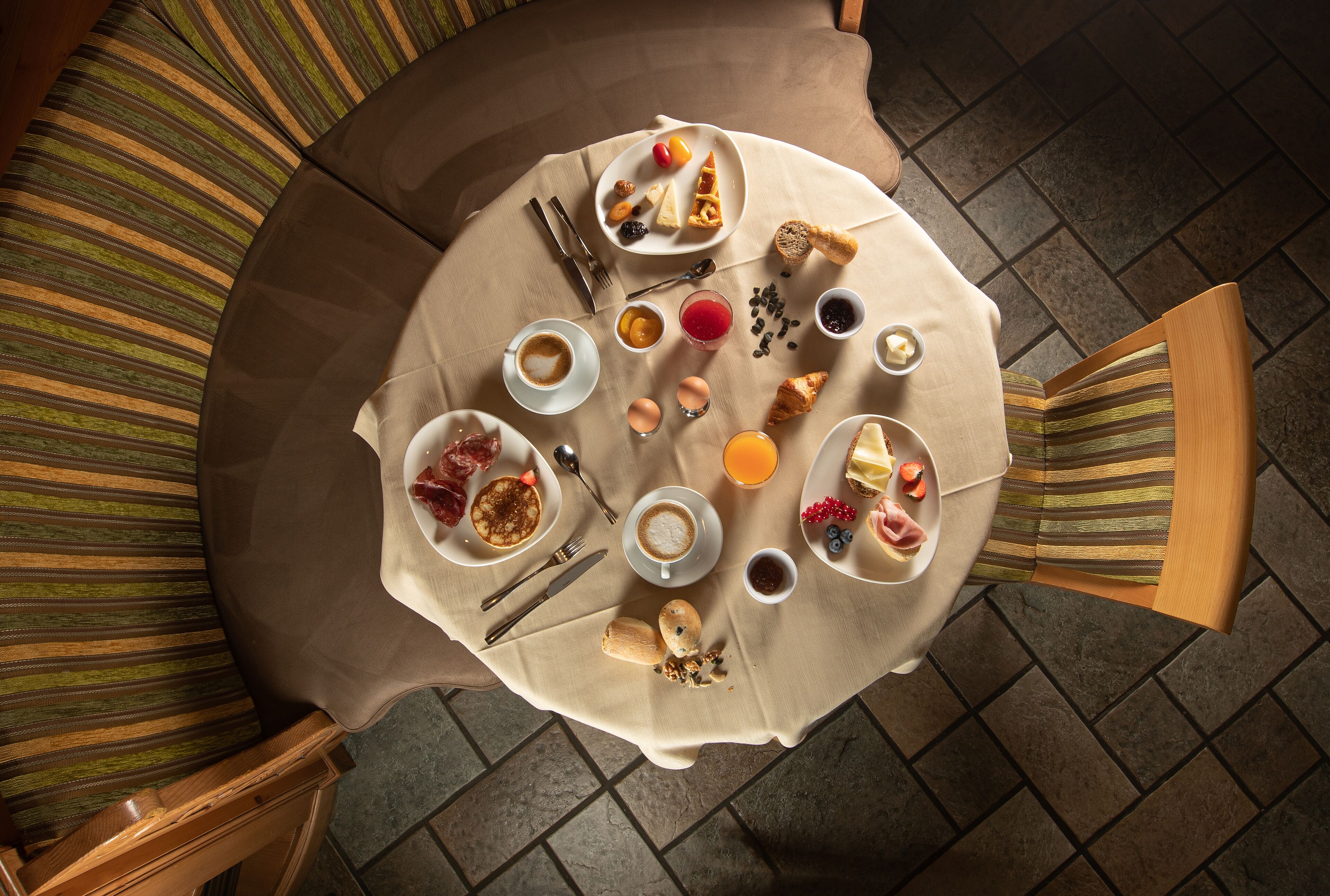 A round table with breakfast items including eggs, toast, and fruit, surrounded by striped chairs.