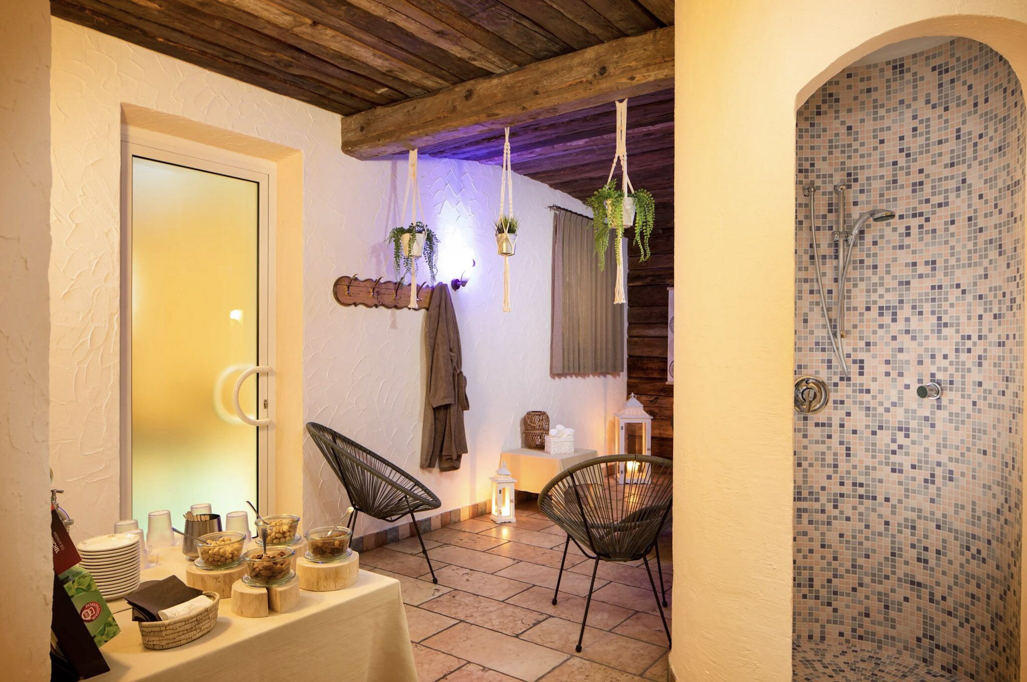 Een gezellige kamer met een betegelde douche, een tafel met lekkernijen en hangplanten.