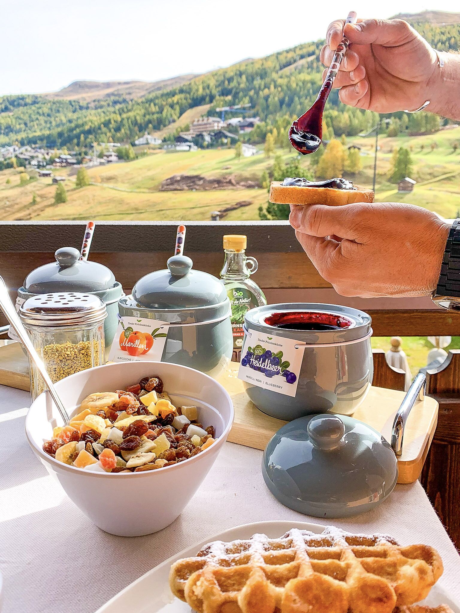 A breakfast table with a bowl of cereal, a waffle, and condiments.