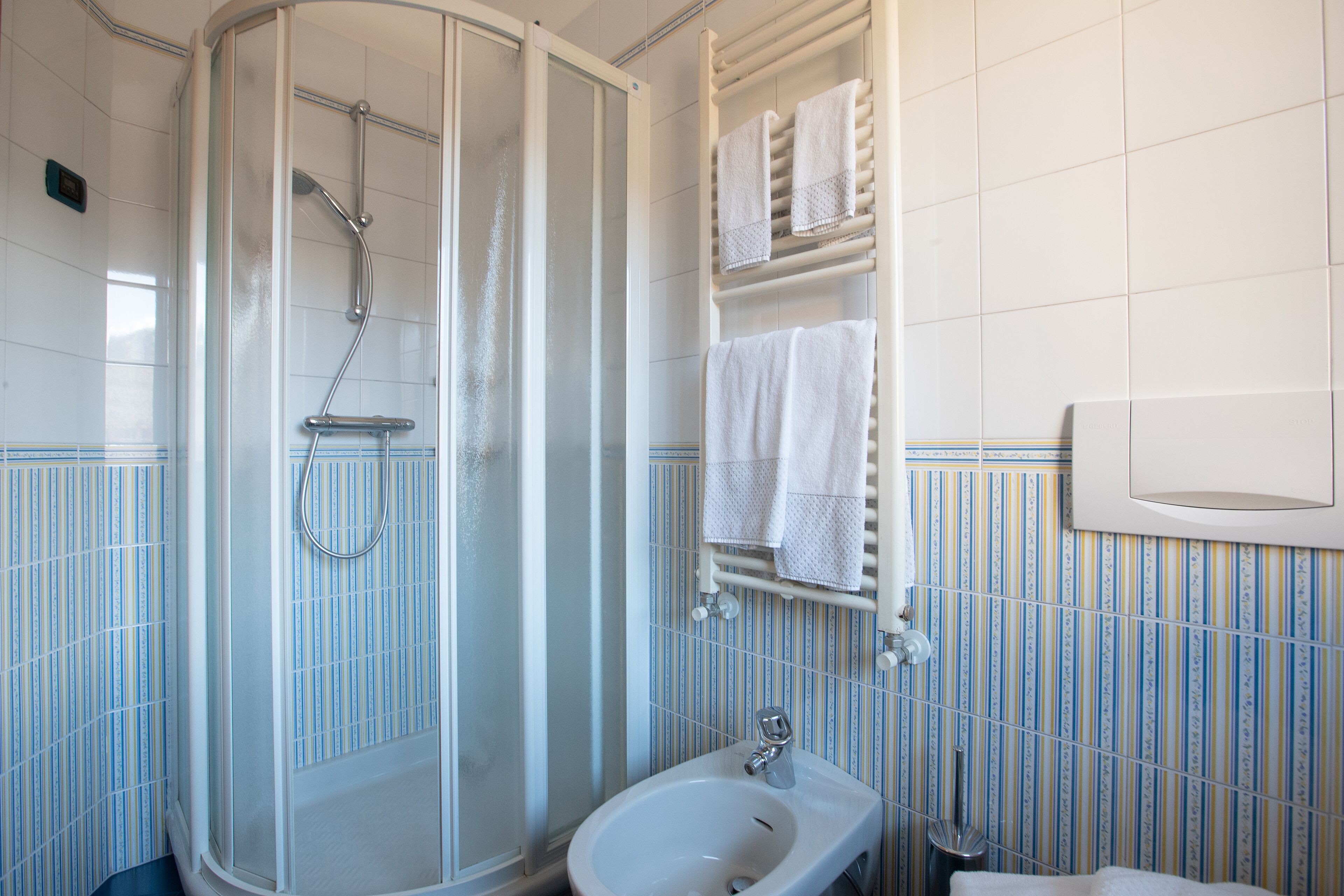 Une salle de bain avec une douche à parois de verre, un lavabo et un porte-serviettes avec plusieurs serviettes.