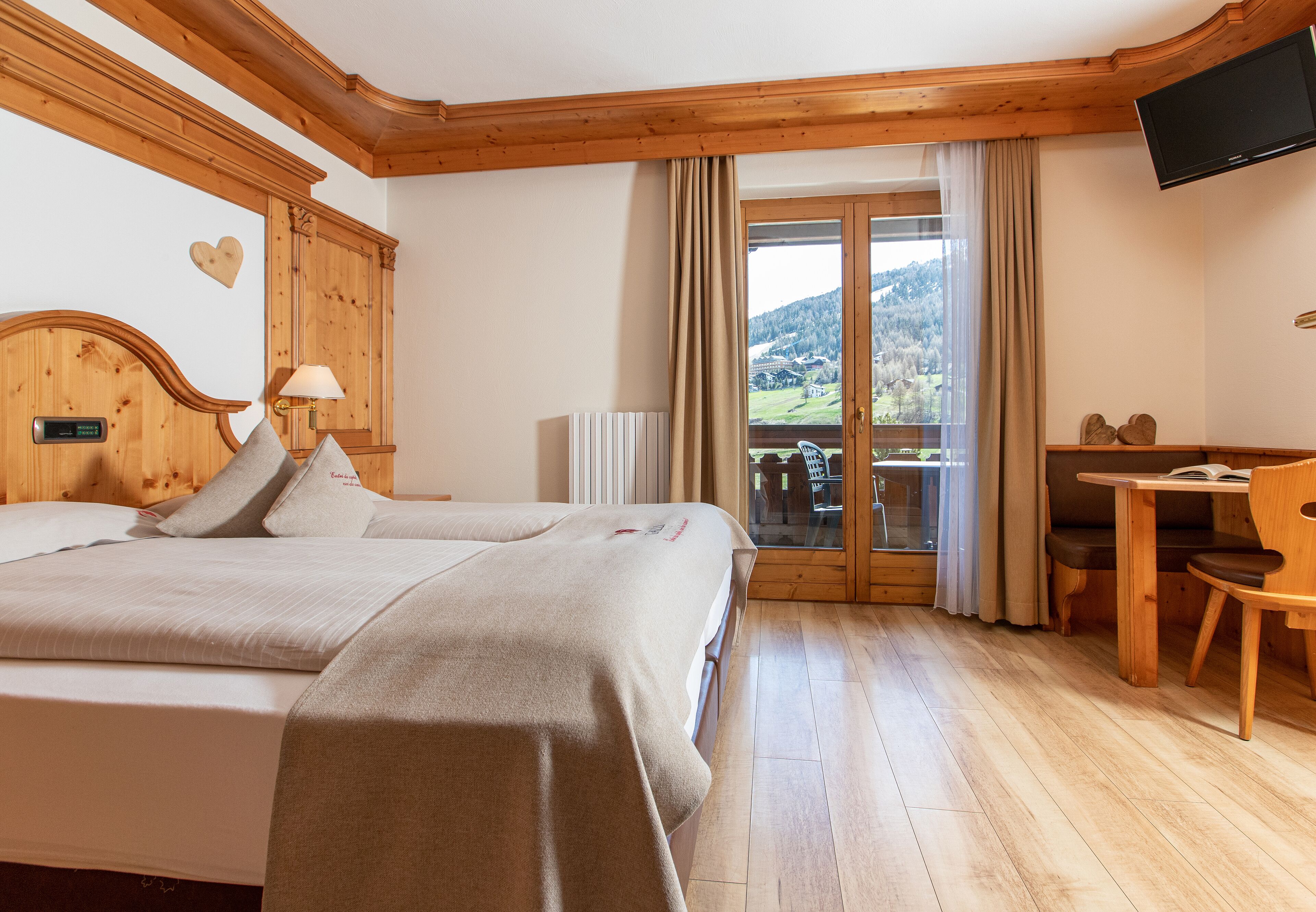 A hotel room with a wooden bed, a desk, and a view of the outdoors.