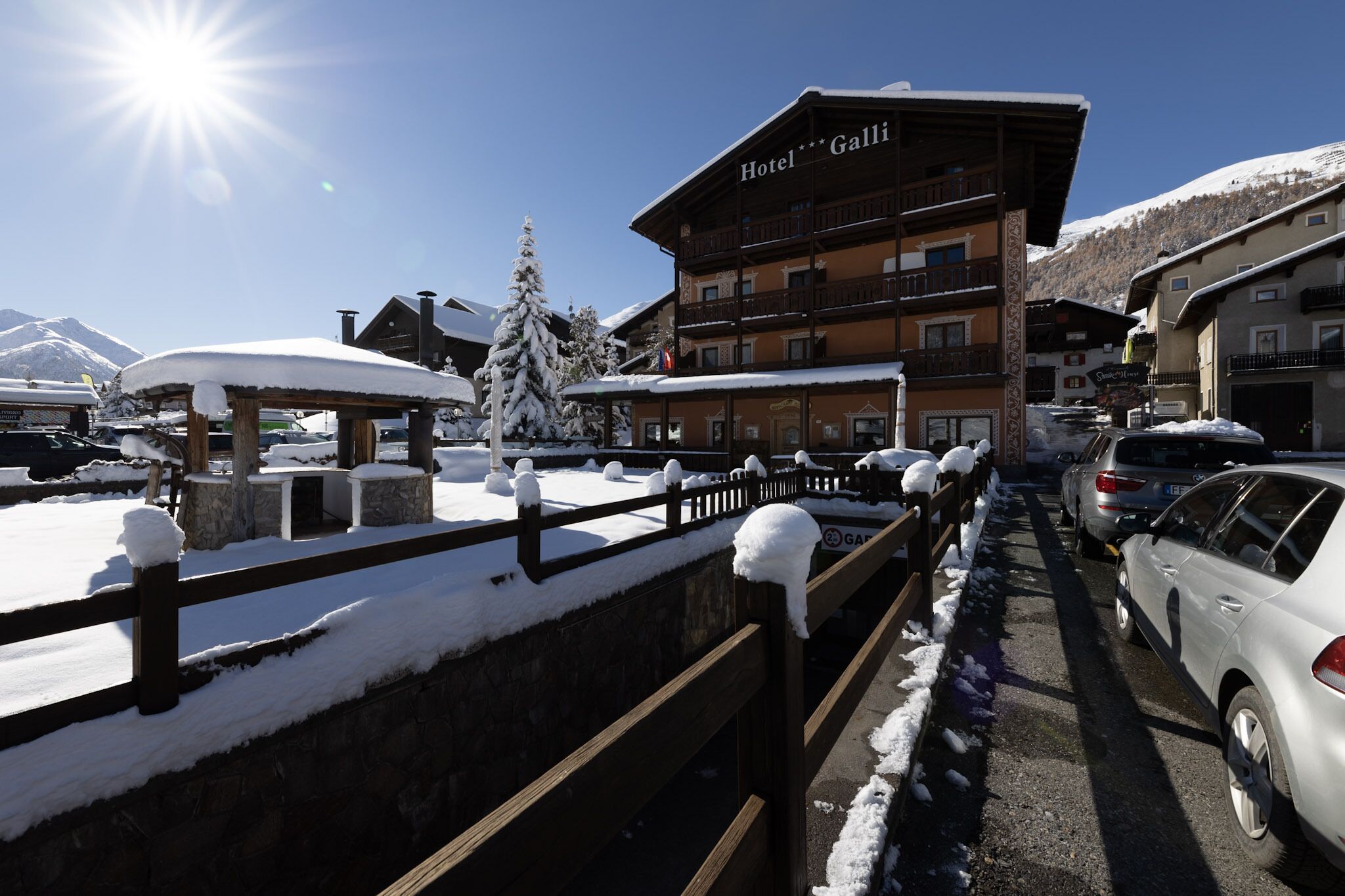 A hotel with multiple floors, a covered outdoor area, and a view of snow-covered mountains.