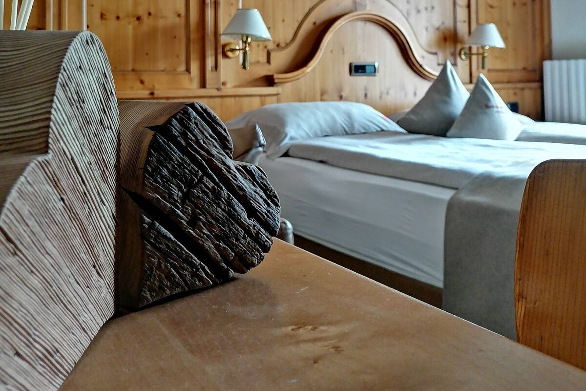 A hotel room with wooden paneling, two beds with pillows, and two bedside lamps.