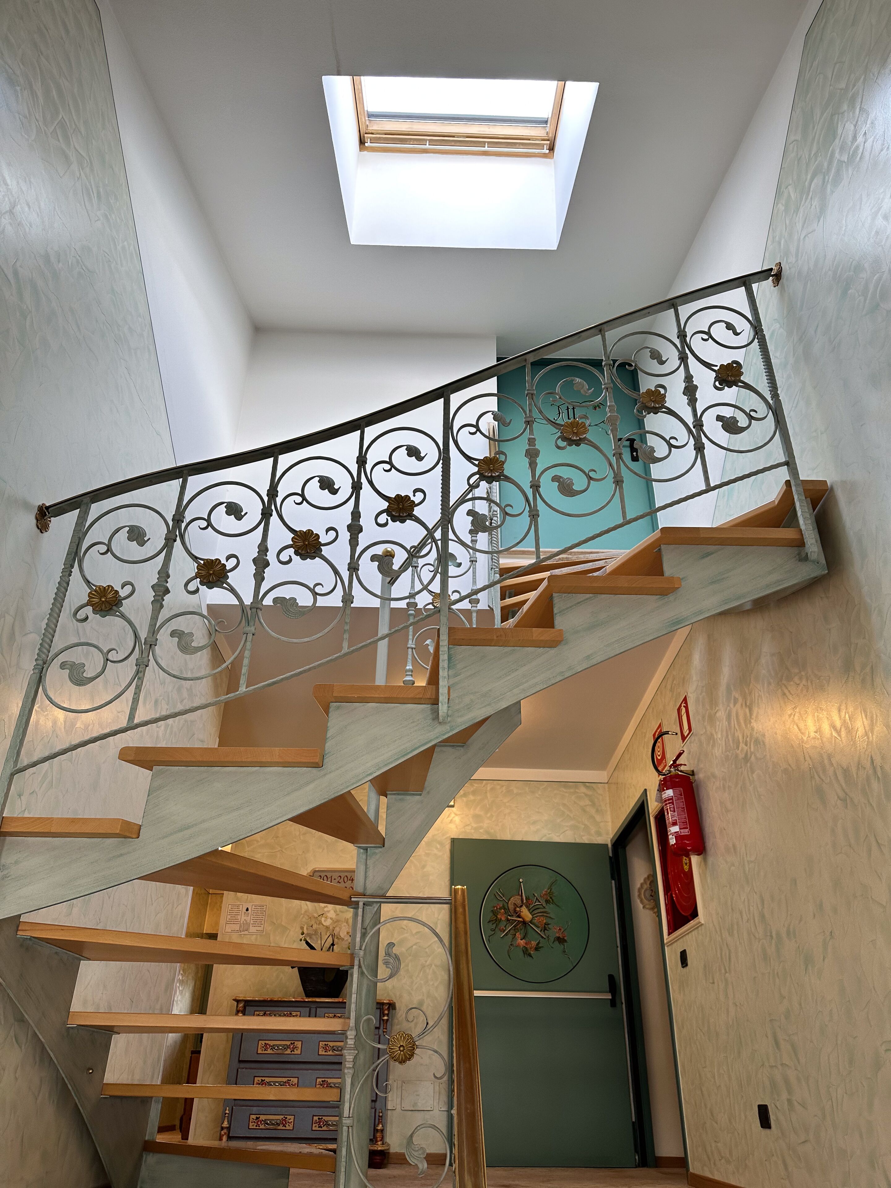 A staircase with a metal railing and a skylight above.