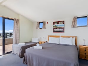 A hotel room with two beds, a large window, a painting, and a view of the sky. - Boatshed Motel Apartments (Tauranga)