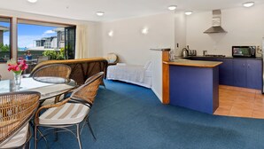 A modern hotel room with a dining area, a kitchenette, and a view of the sea.