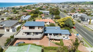 A residential area with houses, a road, and a beach in the background.