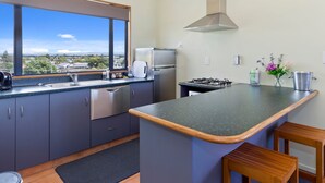 A modern kitchen with a large window, stainless steel appliances, and a view of the city.
