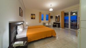 Quarto de hotel com duas camas, uma escrivaninha, uma cadeira, um telefone e vista para o exterior pela janela.