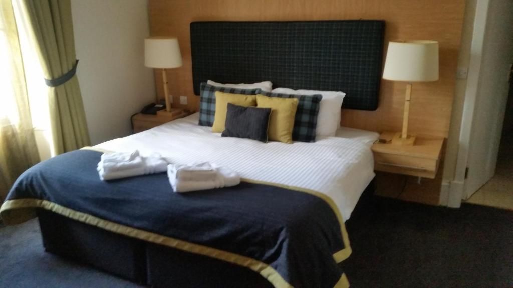 A hotel room with a neatly made bed, two bedside tables with lamps, and a headboard.