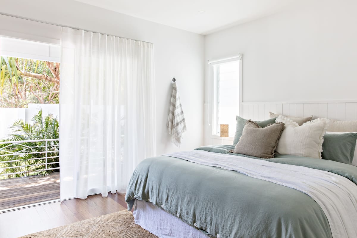 A bedroom with a large bed, a view of greenery outside, and a sliding glass door.