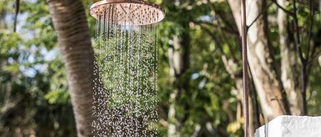 A showerhead with water spraying down, surrounded by greenery.