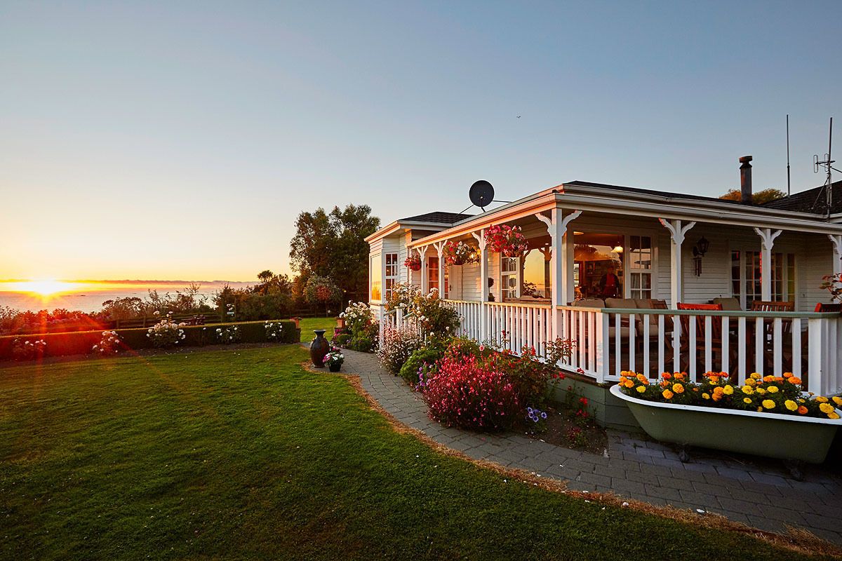 A house with a porch, a garden, and a view of the sunset.