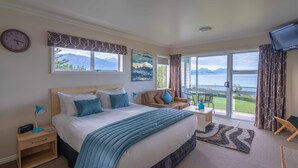 Une chambre avec un grand lit, un bureau, une chaise et une vue sur un lac et des montagnes.
