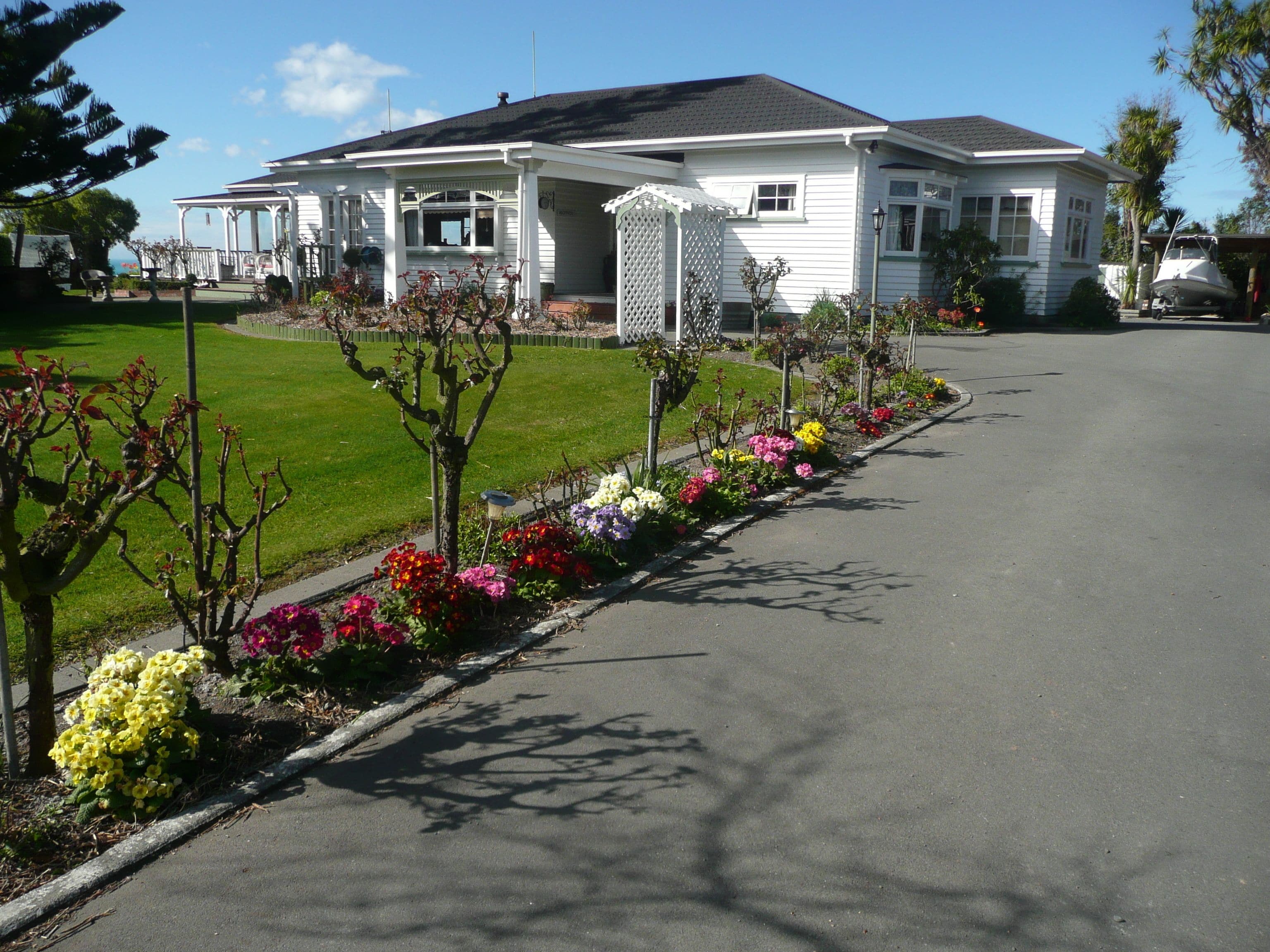 A two-story house with a covered porch, a lawn, and a flower bed along the driveway.