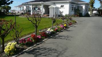 A two-story house with a covered porch, a lawn, and a flower bed along the driveway.