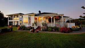Une maison à deux étages dotée d’un porche abrité, d’une antenne parabolique et d’un jardin bien entretenu où poussent différentes sortes de fleurs et d’arbustes.