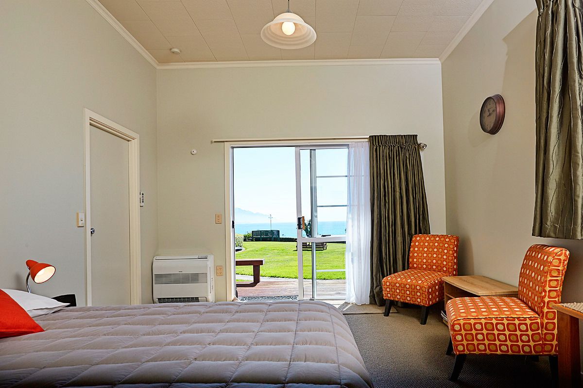 Ein Hotelzimmer mit einem Bett, zwei Stühlen, einem Tisch und Blick ins Freie.