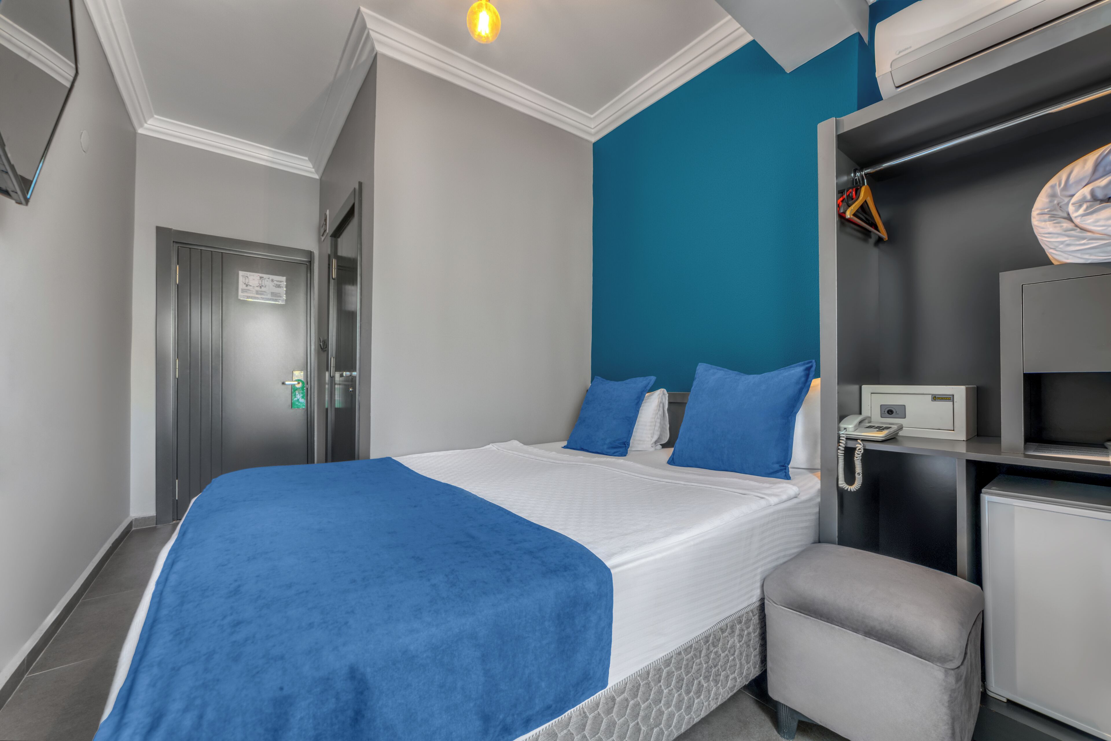A neatly arranged hotel room with a bed, a desk, a chair, and a wardrobe.