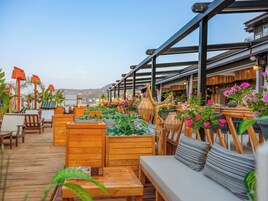 A wooden deck with outdoor seating, including sofas and chairs, surrounded by potted plants and decorative items.