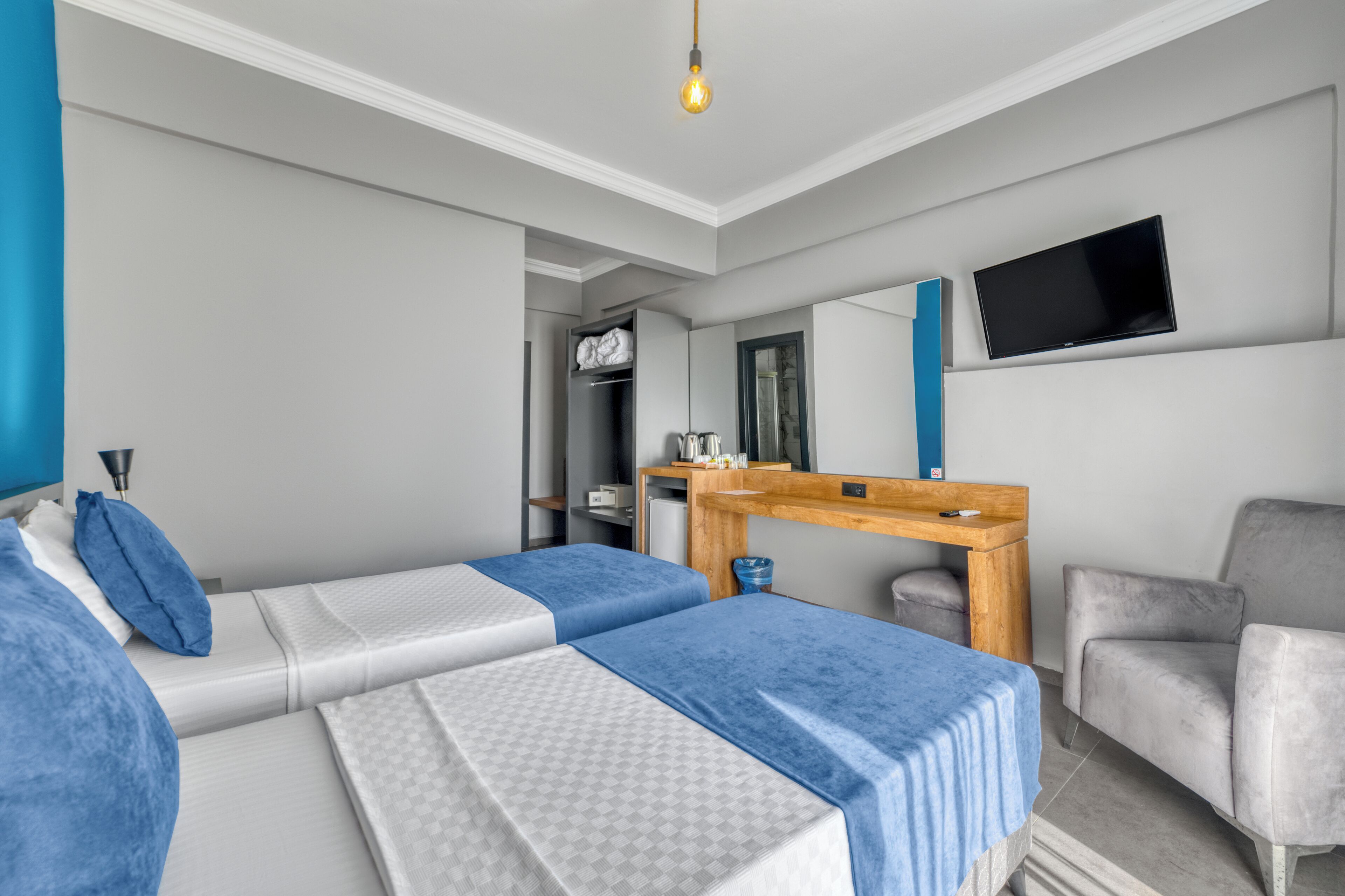 A hotel room with two beds, a desk, a chair, a TV, and a wardrobe.