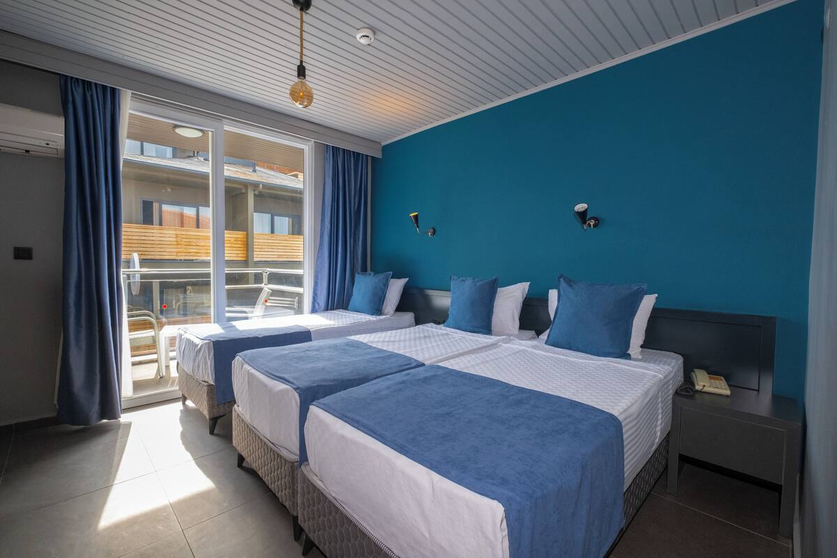 Habitación de hotel con dos camas, un balcón y vista al interior del edificio.