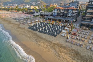 A beachside hotel with rows of sun loungers, umbrellas, and beach chairs.