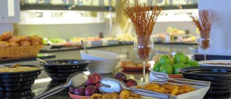 A buffet with various food items including fruits, vegetables, and pastries.