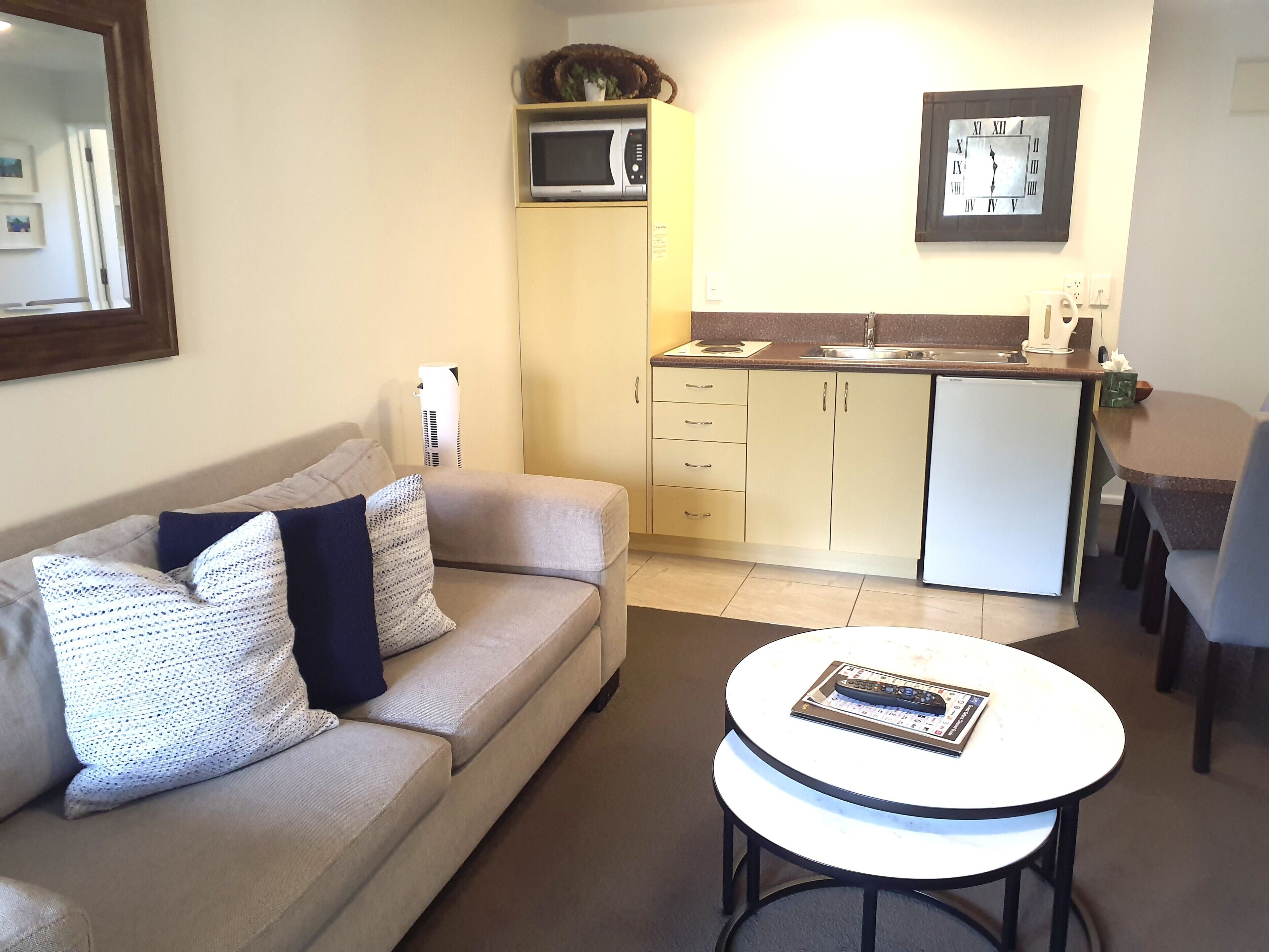 A compact living space with a sofa, a small round table, a kitchenette, and a dining area.