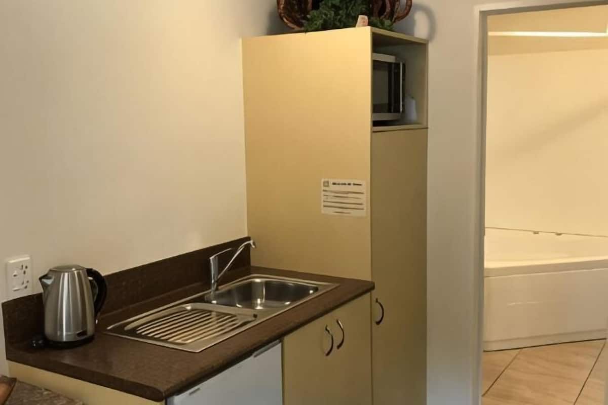 A compact kitchenette with a sink, a kettle, and a microwave.