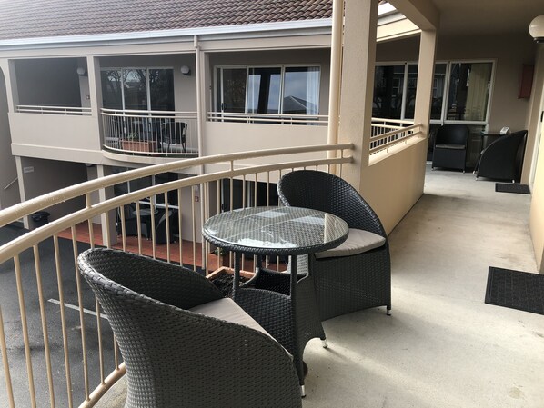 A balcony with wicker furniture, including a table and chairs, and a view of the building's exterior.
