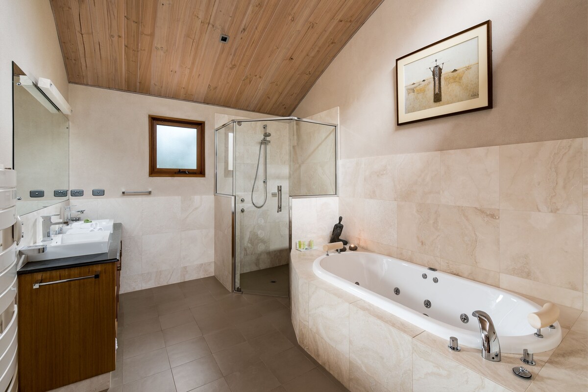 Ein modernes Badezimmer mit einer gläsernen Duschkabine, einer großzügigen freistehenden Badewanne und einer Holzbeschichtung an der Decke.