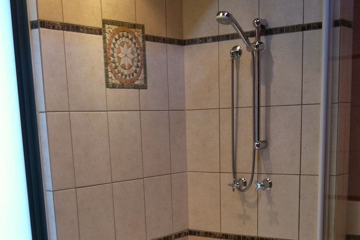 Ein modernes Badezimmer mit einer großen Badewanne, einer Duschkabine und einem Fenster.