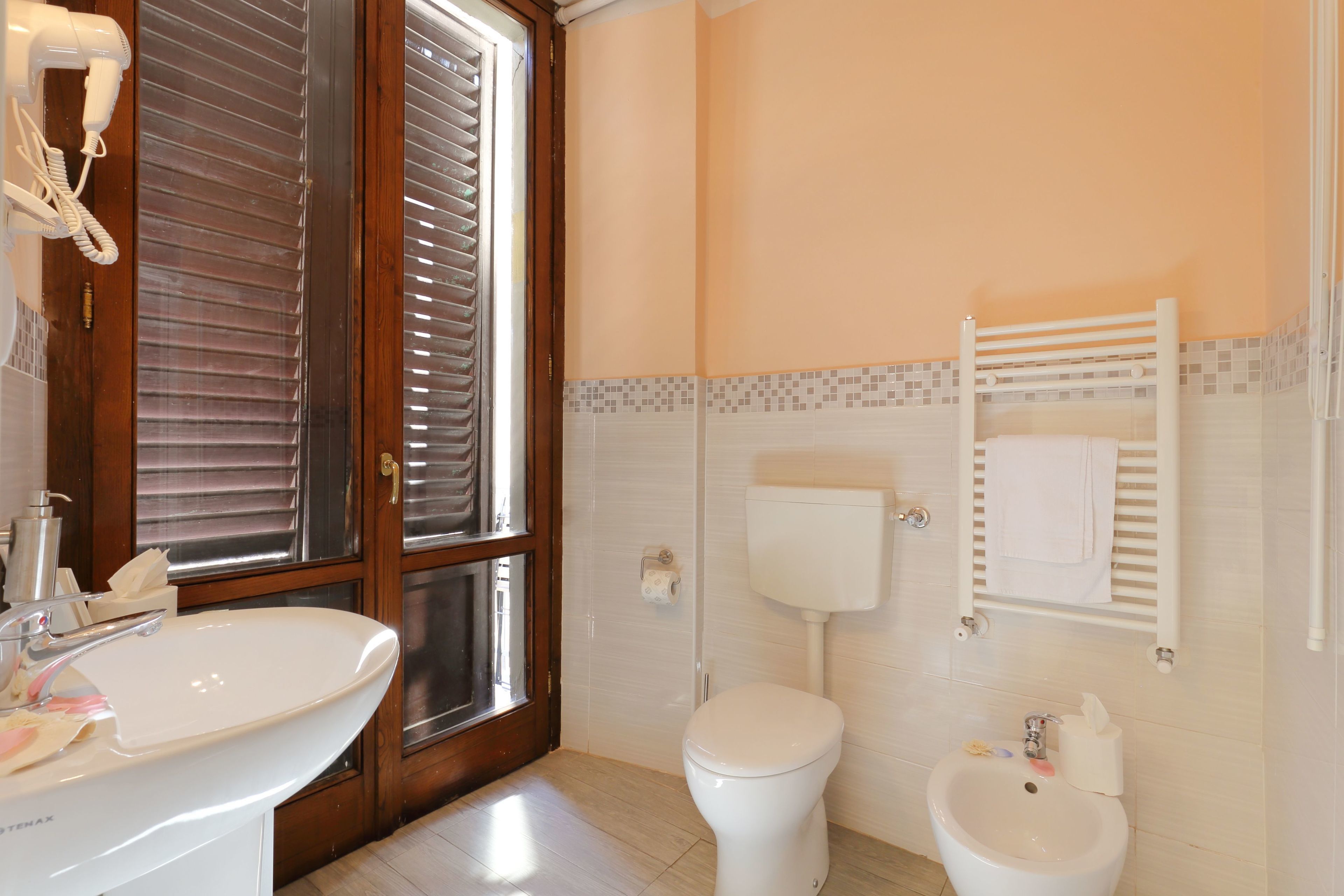 Une salle de bain équipée d’un lavabo, de toilettes, d’un bidet et d’un porte-serviettes.