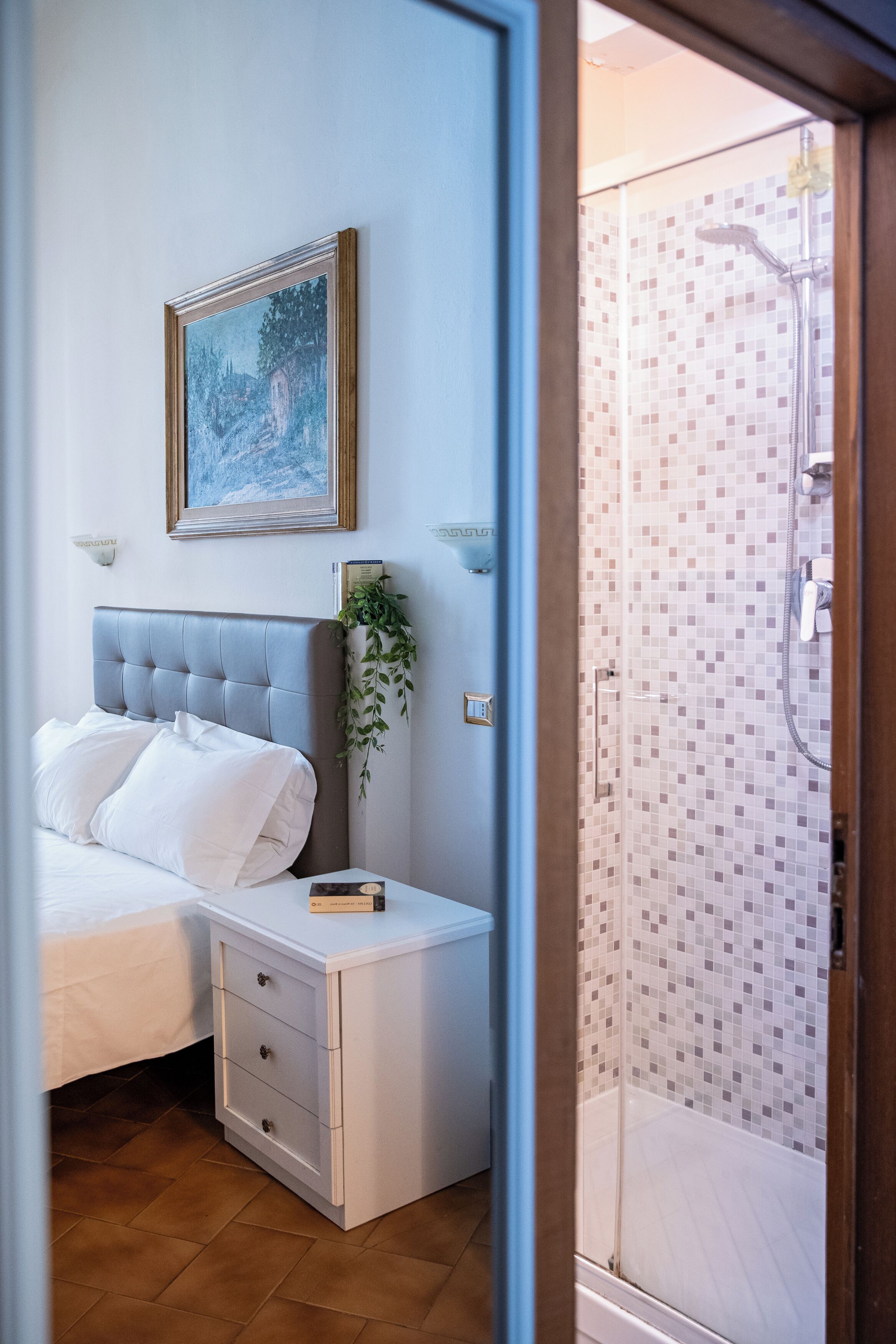 A bedroom with a bed, bedside table, and a painting on the wall.