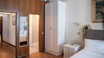 Quarto com guarda-roupa, mesa de cabeceira, cama, espelho e estante de livros.