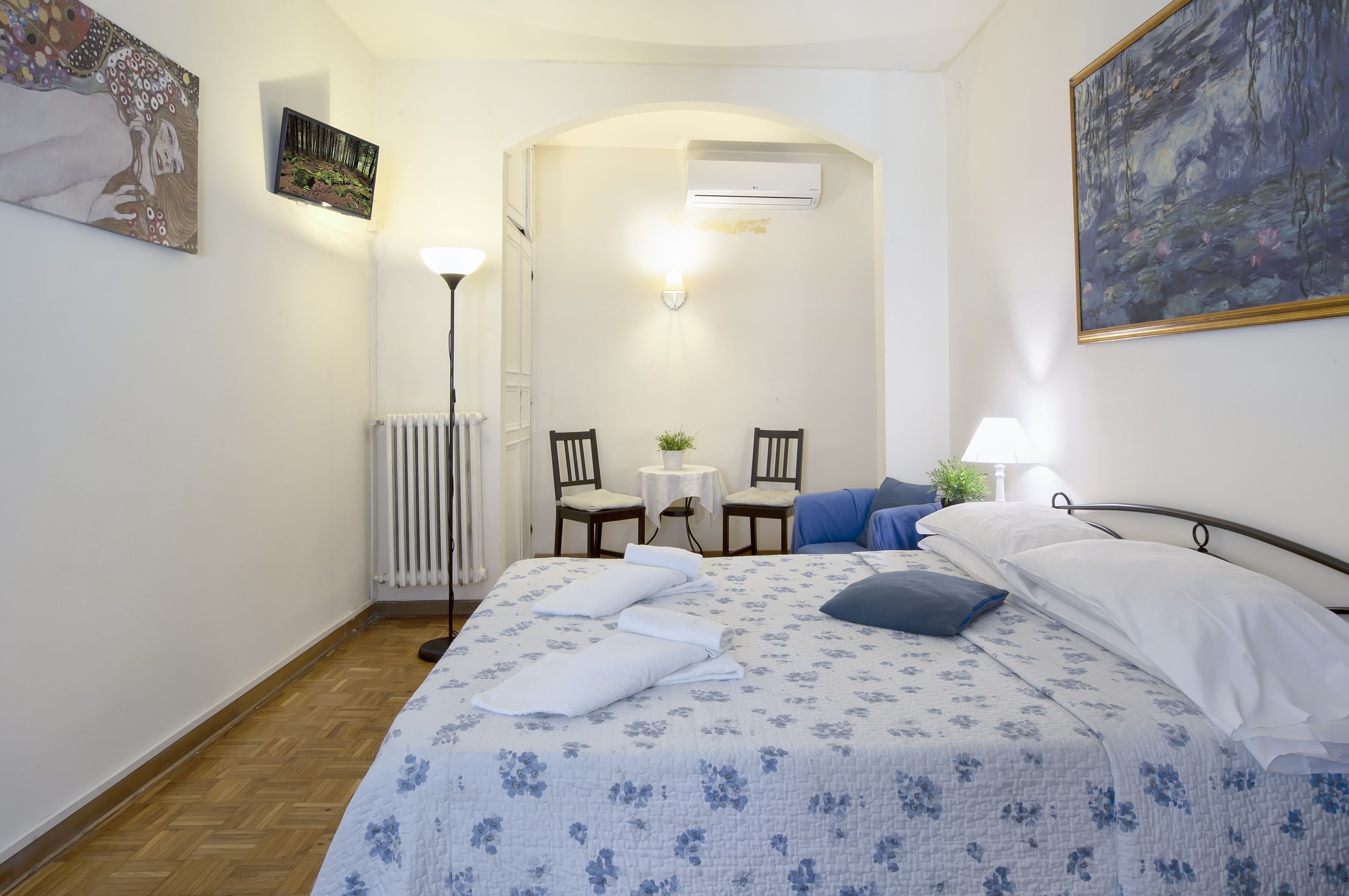 A bedroom with a bed, two chairs, a small table, and a radiator.