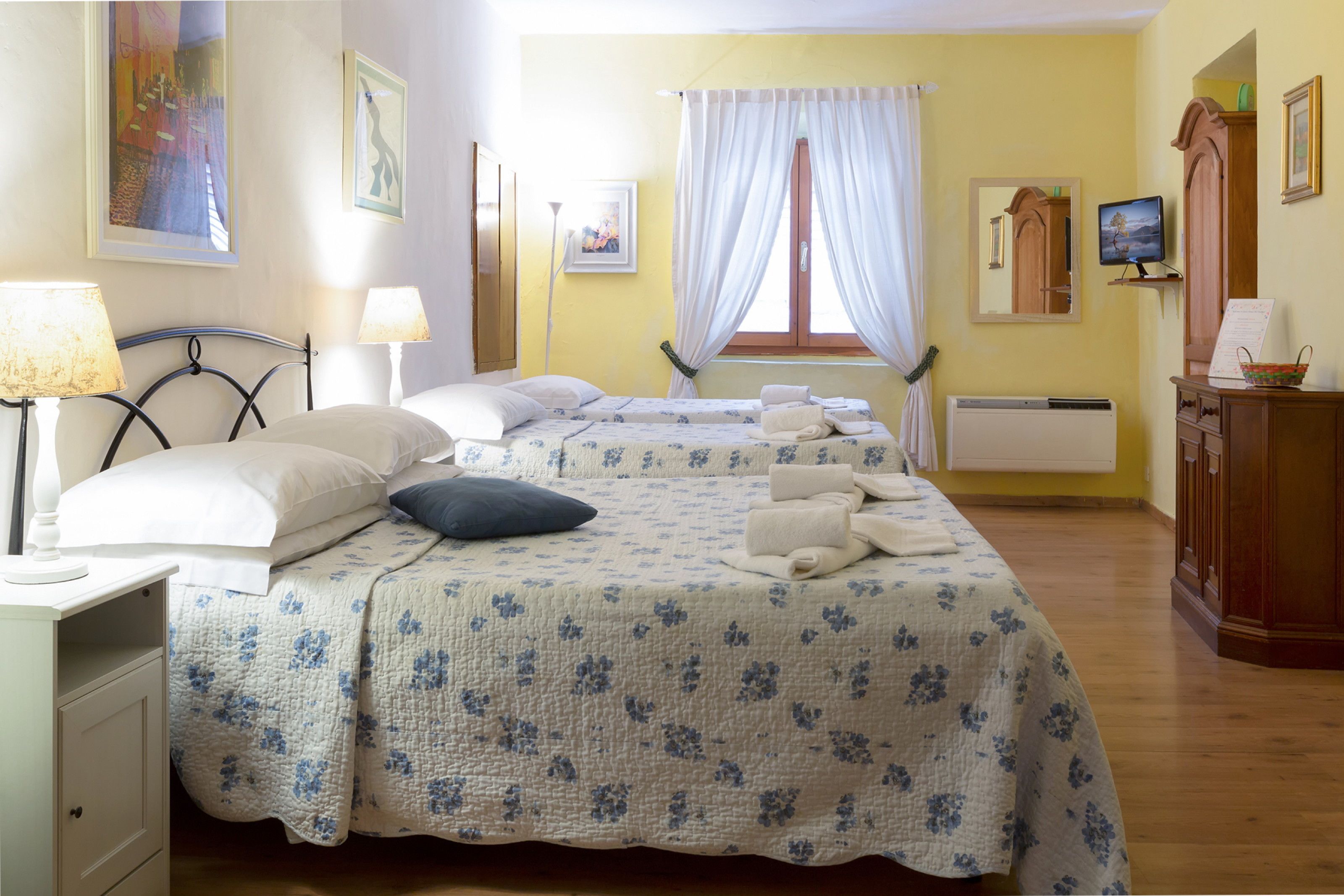 Une chambre d’hôtel avec deux lits, un bureau, une chaise, une télévision et une fenêtre avec des rideaux.