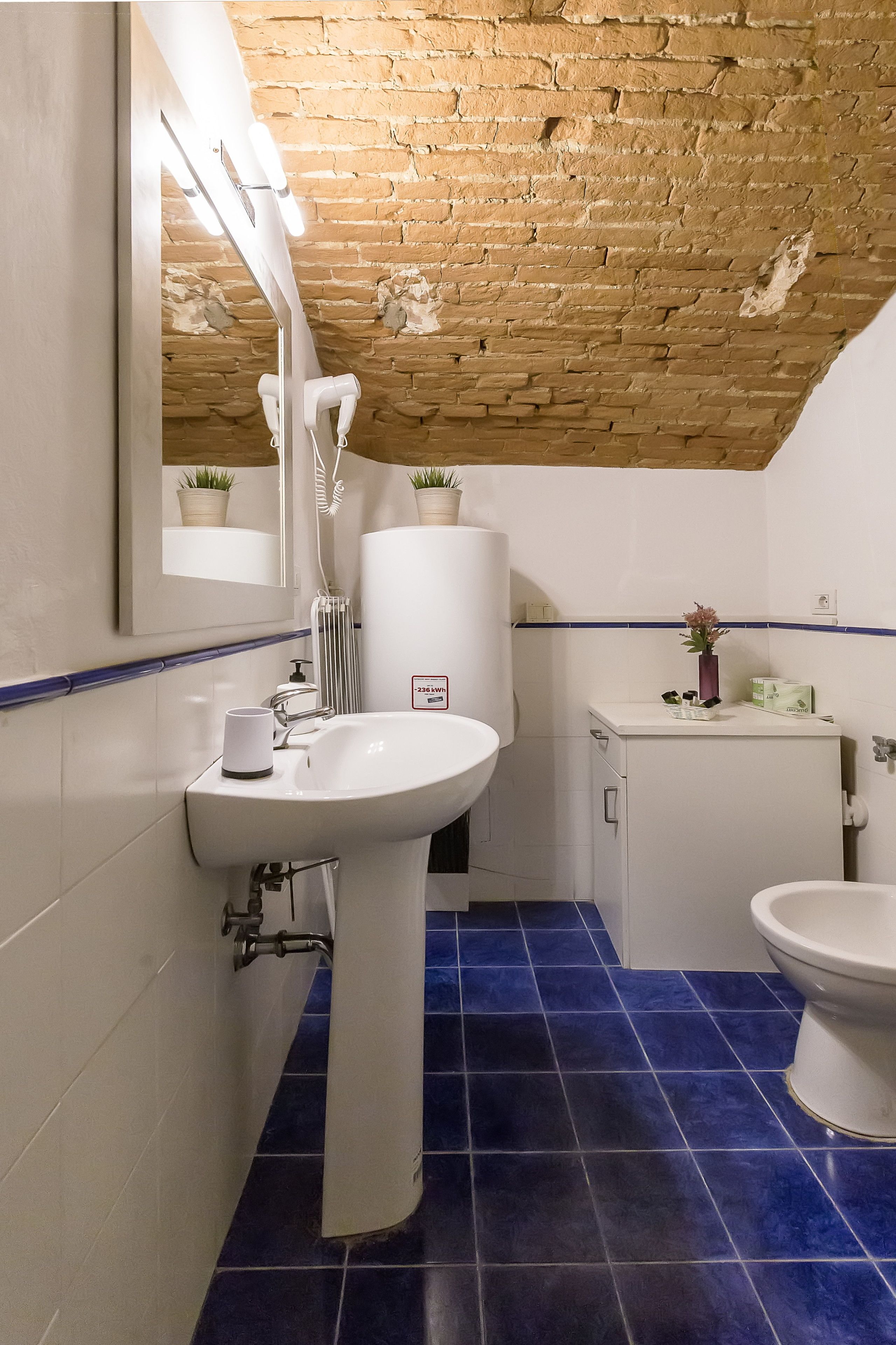 A bathroom with a white sink, a mirror, a white toilet, and a blue-tiled floor.