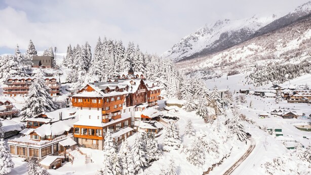 A snow-covered mountain resort with wooden buildings, ski slopes, and a ski lift. - Hotel Catedral Patagonia Ski & Wellness (San Carlos de Bariloche)