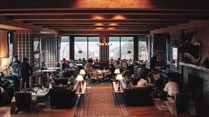 A spacious, well-lit lounge area with wooden beams, comfortable seating, and large windows offering views of the outdoors. - Hotel Catedral Patagonia Ski & Wellness (San Carlos de Bariloche)