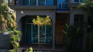 A two-story house with a balcony, large windows, and a paved pathway leading to the entrance. - Oceanic Villa (Grand-Baie)