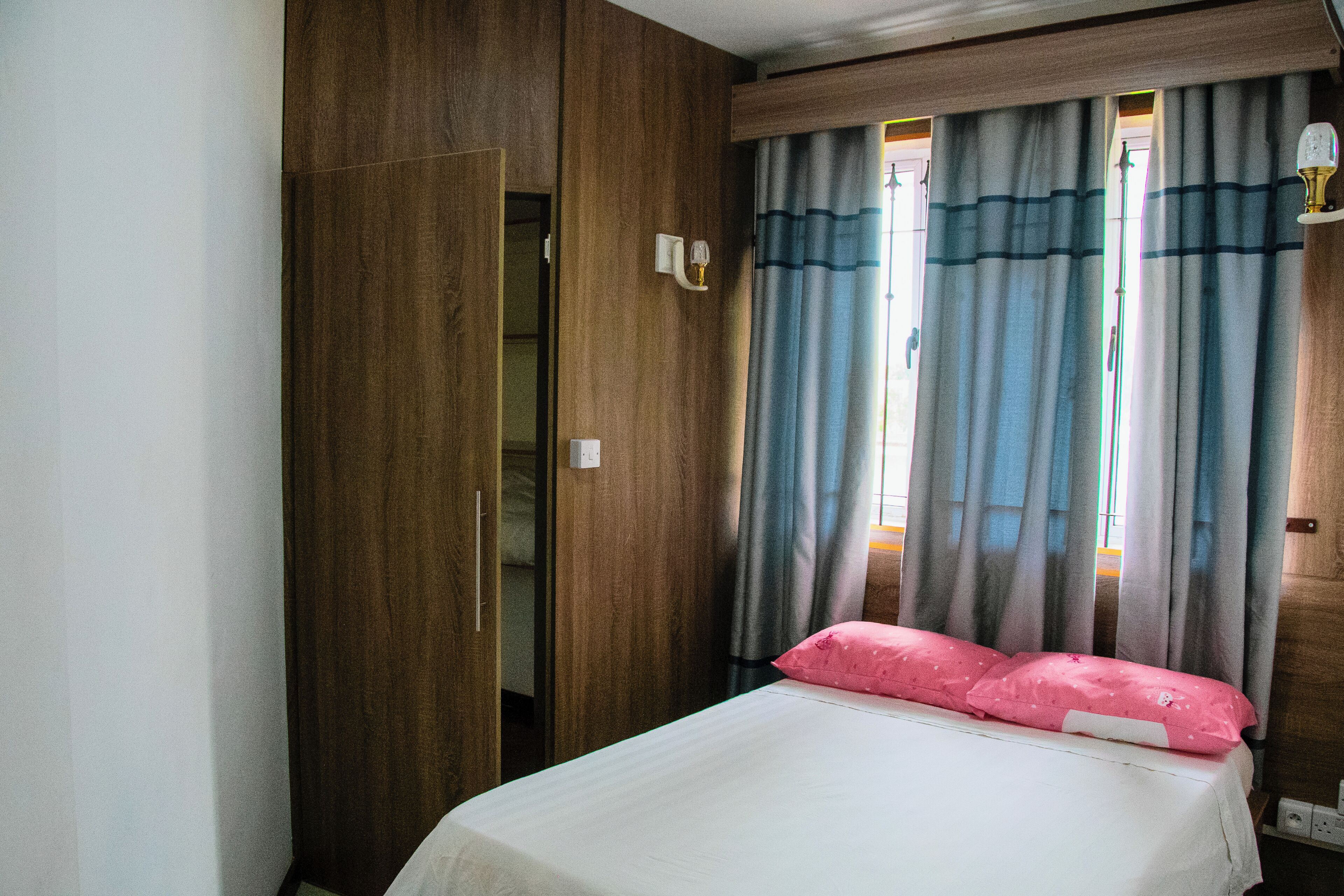 Un dormitorio con una cama, un armario de madera y una ventana con cortinas.