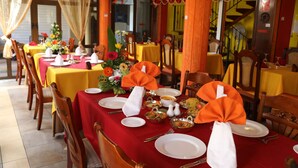 A restaurant with tables set for dining, featuring yellow tablecloths and red napkins. - Oceanic Villa (Grand-Baie)