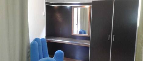 A room with a large wardrobe, a bench, and a blue chair.