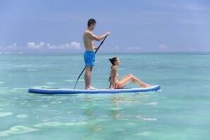 Dos personas haciendo paddleboard en aguas cristalinas.