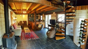 Ein rustikales Interieur mit einer Holztreppe, einem Kamin, einem Essbereich und einer Küche.