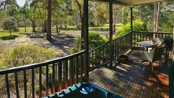 Relax in a serene outdoor space with a hot tub and dining area surrounded by lush greenery.