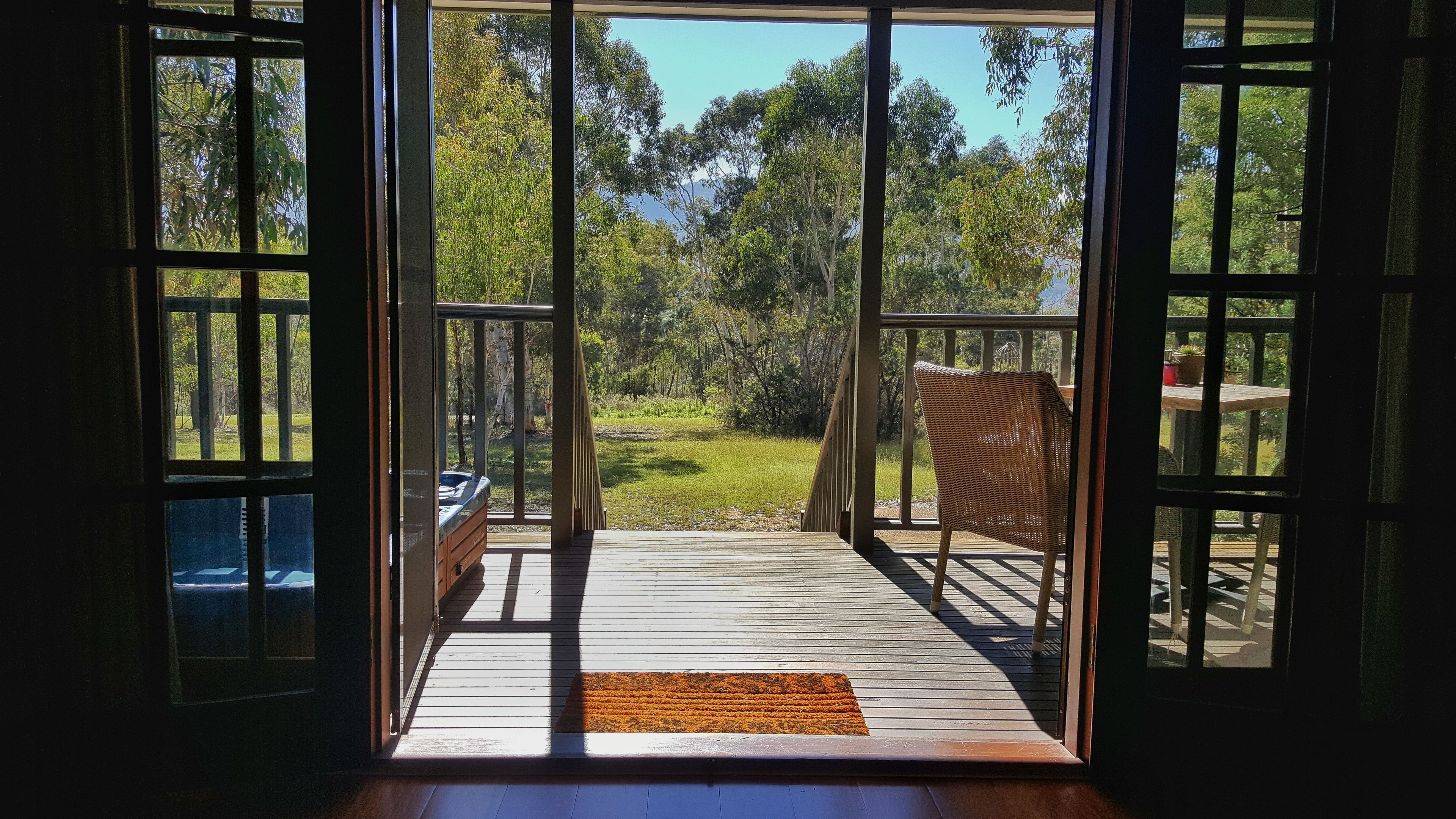 A wooden deck with a view of a grassy area and trees.