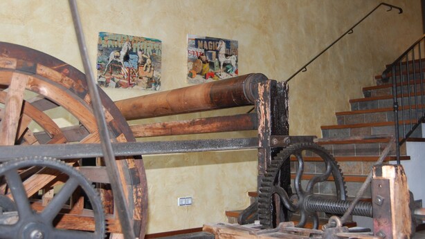 A room with a large wooden wheel and a staircase. - Hotel Molí de la Torre (Bigues I Riells)